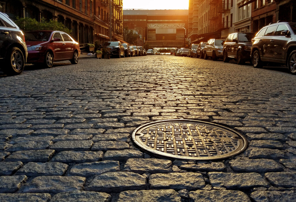 sunlight-shining-on-cobblestone-street-manhole